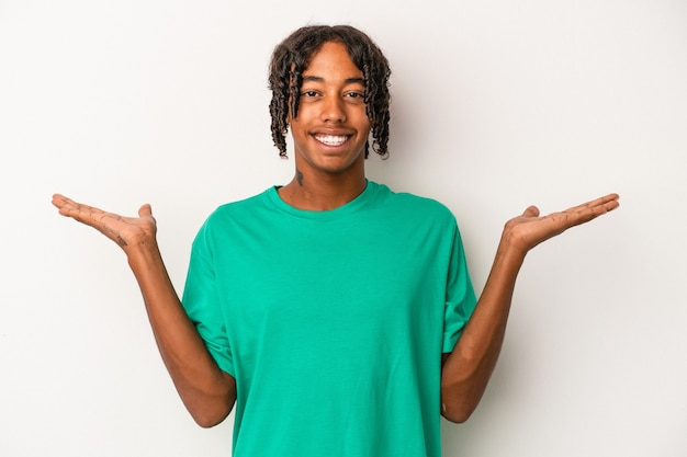 Young african american man isolated on white background makes scale with arms, feels happy and confident.