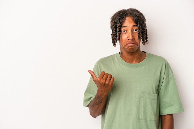 Young african american man isolated on white background shocked pointing with index fingers to a copy space.