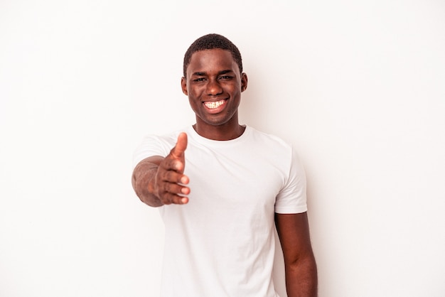 Young african american man isolated on white background stretching hand at camera in greeting gesture.