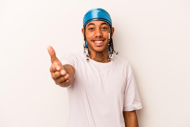 Young African American man isolated on white background stretching hand at camera in greeting gesture