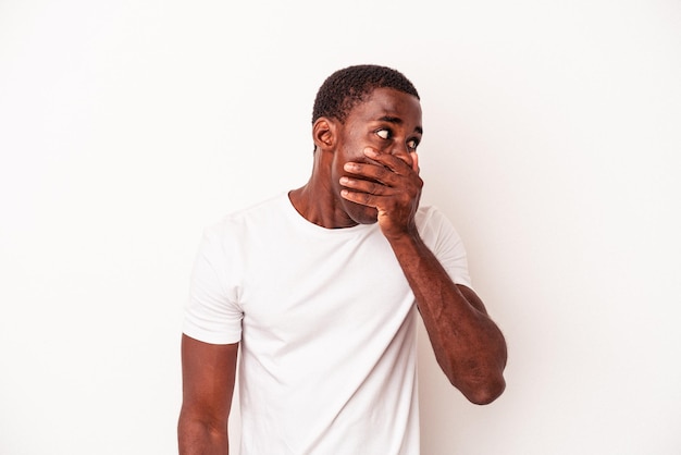 Photo young african american man isolated on white background thoughtful looking to a copy space covering mouth with hand.