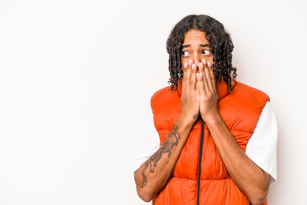 Young African American man isolated on white background thoughtful looking to a copy space covering mouth with hand