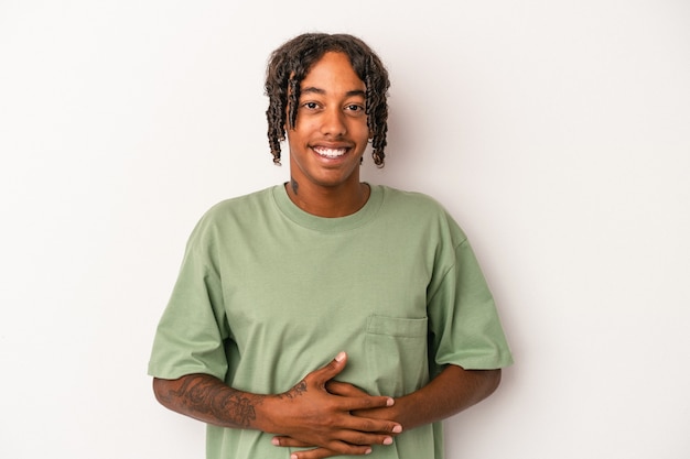 Young african american man isolated on white background touches tummy, smiles gently, eating and satisfaction concept.