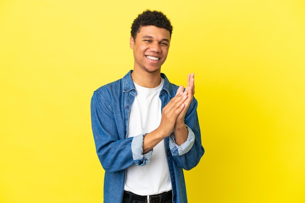 Young African American man isolated on yellow background applauding after presentation in a conference