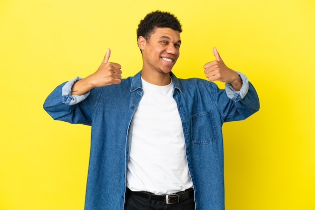 Young African American man isolated on yellow background giving a thumbs up gesture