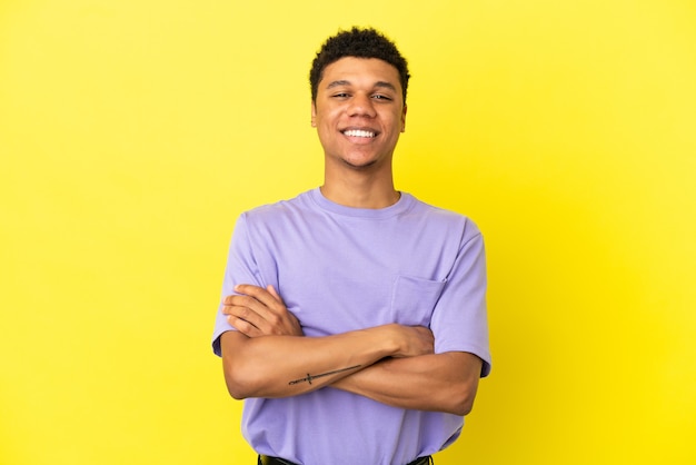 Young African American man isolated on yellow background keeping the arms crossed in frontal position