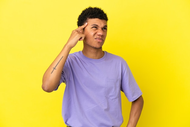 Young African American man isolated on yellow background making the gesture of madness putting finger on the head