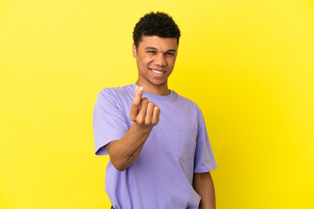 Foto giovane uomo afroamericano isolato su sfondo giallo che fa soldi gesture