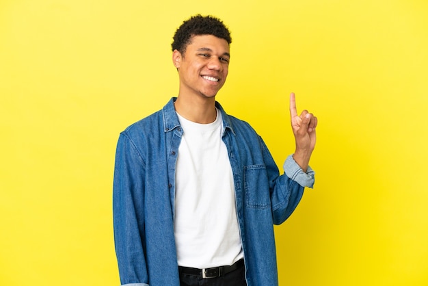 Young African American man isolated on yellow background showing and lifting a finger in sign of the best