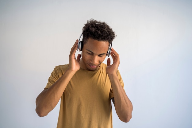 Young african american man listening to funky music using wireless headphones.