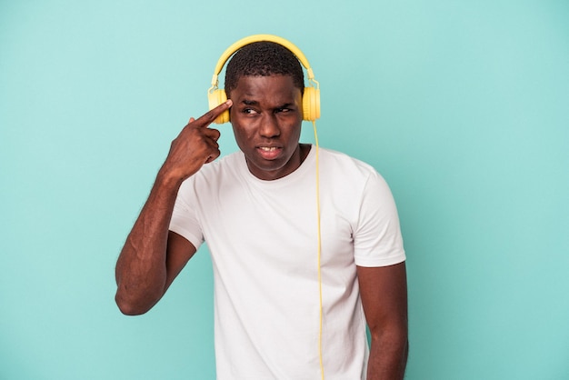 Young African American man listening to music isolated on blue background showing a disappointment gesture with forefinger