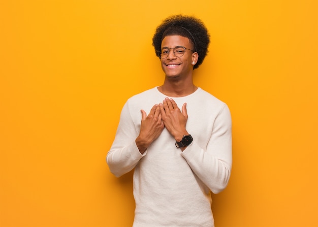 Photo young african american man over an orange wall doing a romantic gesture