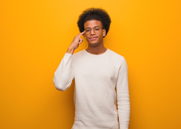 Young african american man over an orange wall thinking about an idea