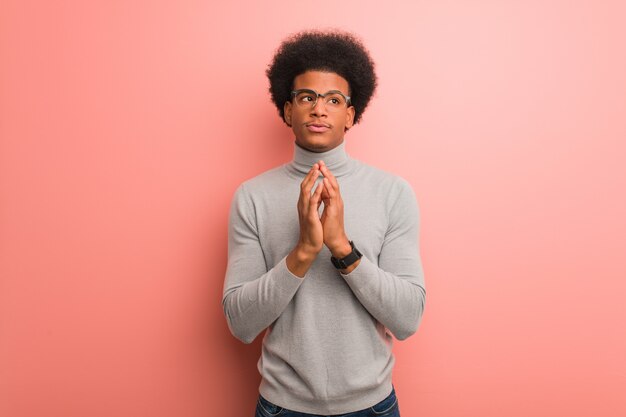 Young african american man over a pink wall devising a plan