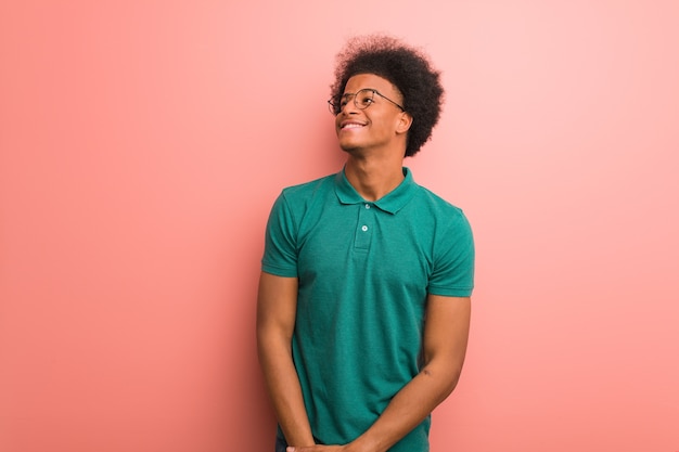 Young african american man over a pink wall dreaming of achieving goals and purposes