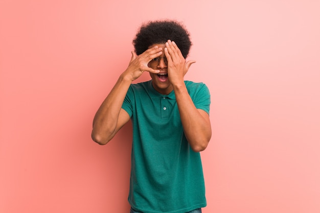 Young african american man over a pink wall feels worried and scared