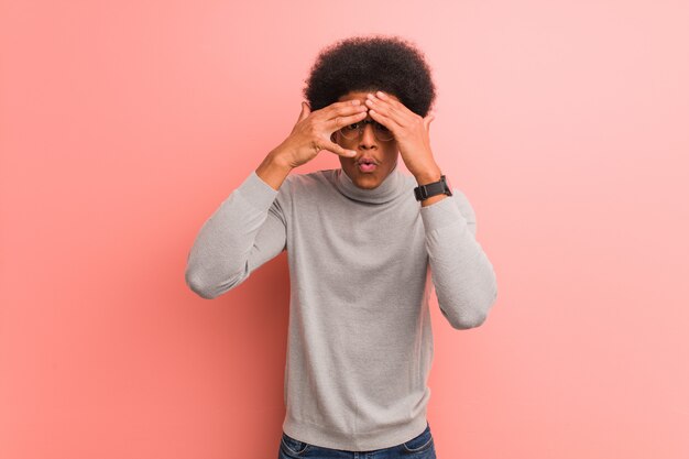 Young african american man over a pink wall feels worried and scared