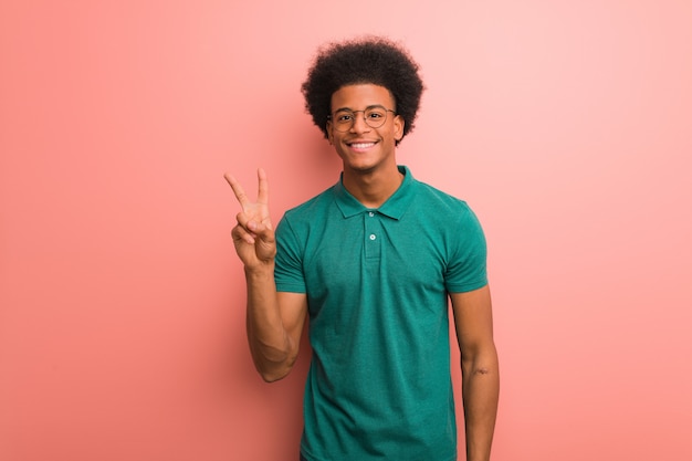 Young african american man over a pink wall fun and happy doing a gesture victory