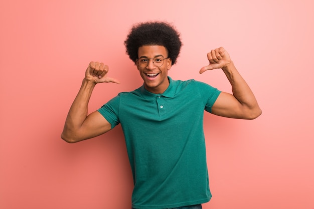 Photo young african american man over a pink wall pointing fingers, example to follow