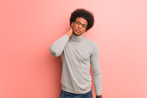 Young african american man over a pink wall suffering neck pain