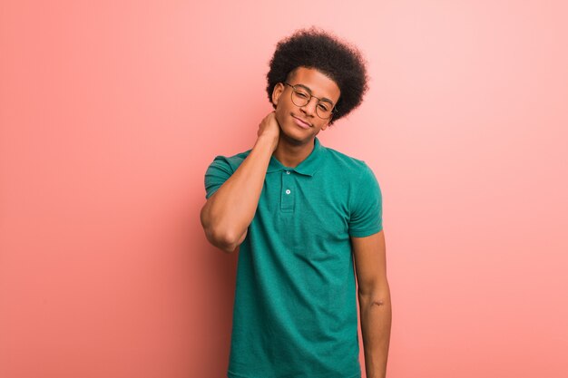 Young african american man over a pink wall suffering neck pain