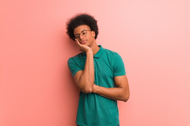 Young african american man over a pink wall tired and very sleepy