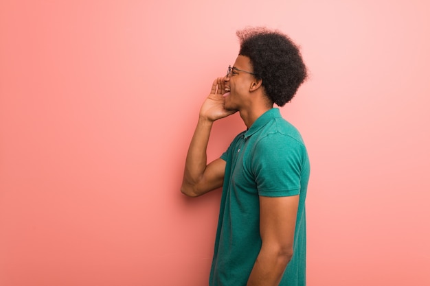 Young african american man over a pink wall whispering gossip undertone