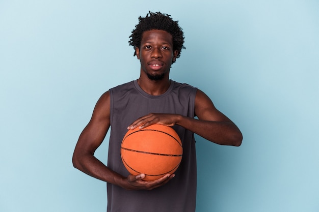 Photo young african american man playing basketball isolated on blue background