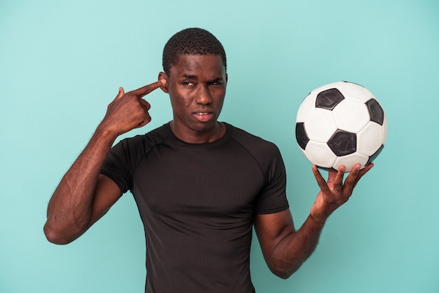 Young African American man playing football isolated on blue background showing a disappointment gesture with forefinger.