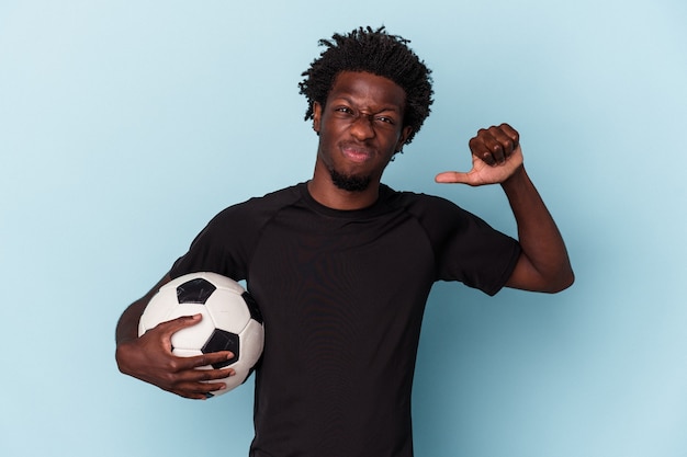 Photo young african american man playing soccer isolated on blue background feels proud and self confident, example to follow.