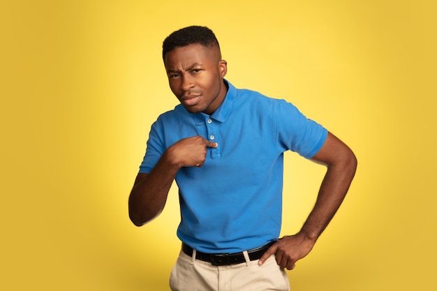 Young african-american man's portrait isolated on yellow, facial expression.