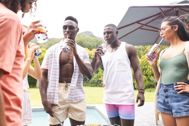 Young African American man sips a drink beside a biracial woman at a pool party