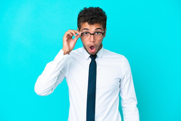 Young african american man sitting on the floor with glasses and surprised