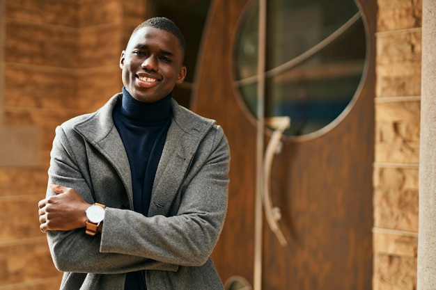 Young african american man smiling happy with crossed arms at the city