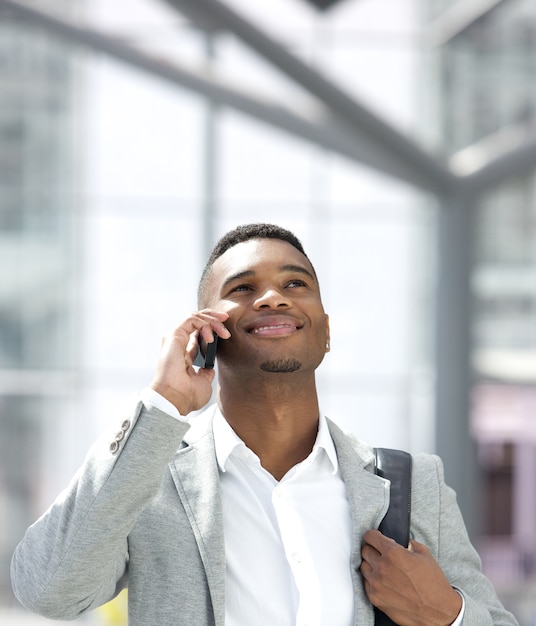 Giovane uomo afroamericano che sorride con il telefono cellulare