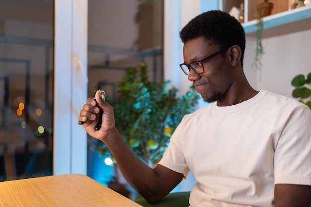 Молодой афроамериканец ухаживает за запястьем руки с помощью эспандера во время долгой работы на компьютере