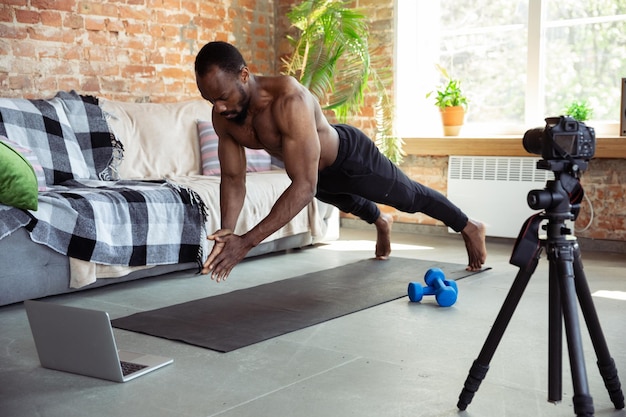 Young african-american man teaching at home online courses of fitness