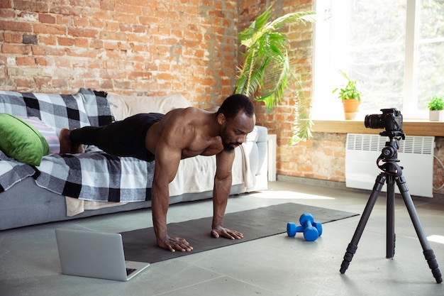 Photo young african-american man teaching at home online courses of fitness