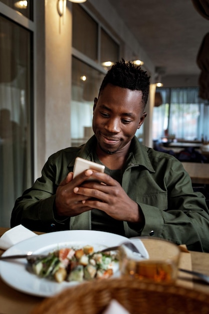 Giovane uomo afroamericano che usa il computer portatile nella caffetteria