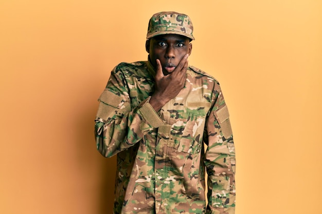 Young african american man wearing army uniform looking fascinated with disbelief, surprise and amazed expression with hands on chin