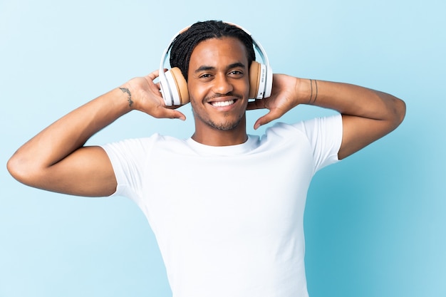 파란색 배경 듣는 음악에 고립 된 머리 띠와 젊은 아프리카 계 미국인 남자
