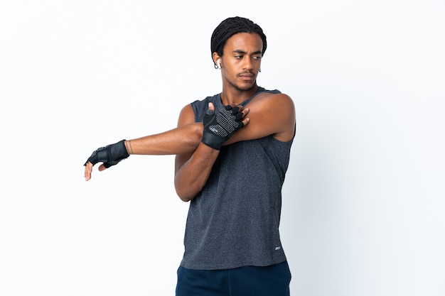 Young African American man with braids isolated on purple background stretching arm