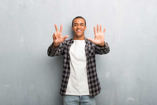 Young african american man with checkered shirt counting eight with fingers