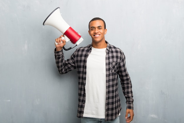 Young african american man with checkered shirt holding a megaphone