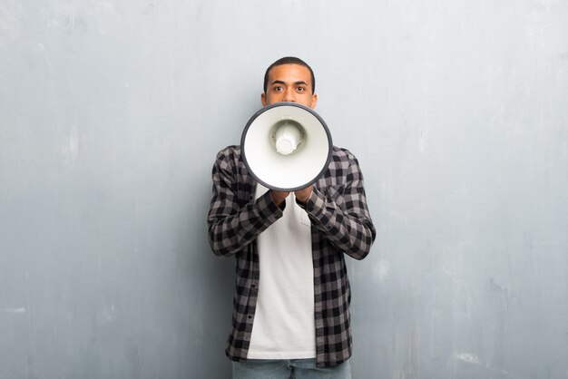 Photo young african american man with checkered shirt shouting through a megaphone to announce something