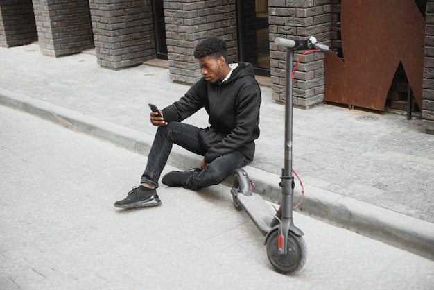 Young african-american man with electric scooter in the city