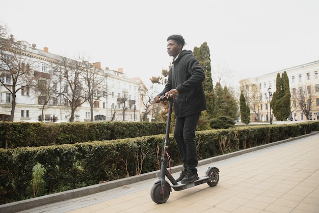 Young african-american man with electric scooter in the city