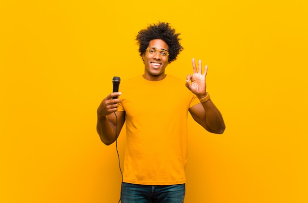 Young african american man with a microphone singing  against or