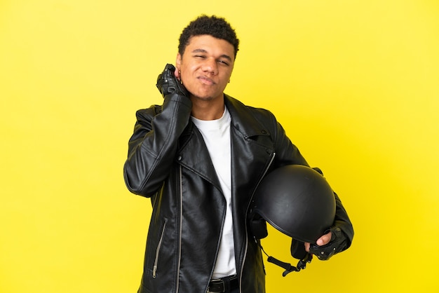 Young African American man with a motorcycle helmet isolated on yellow background frustrated and covering ears