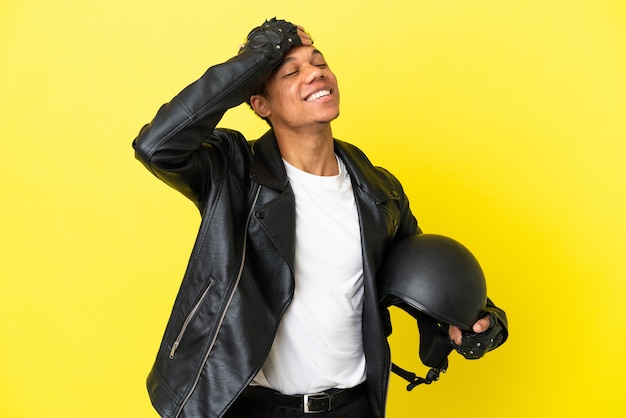 Young African American man with a motorcycle helmet isolated on yellow background smiling a lot